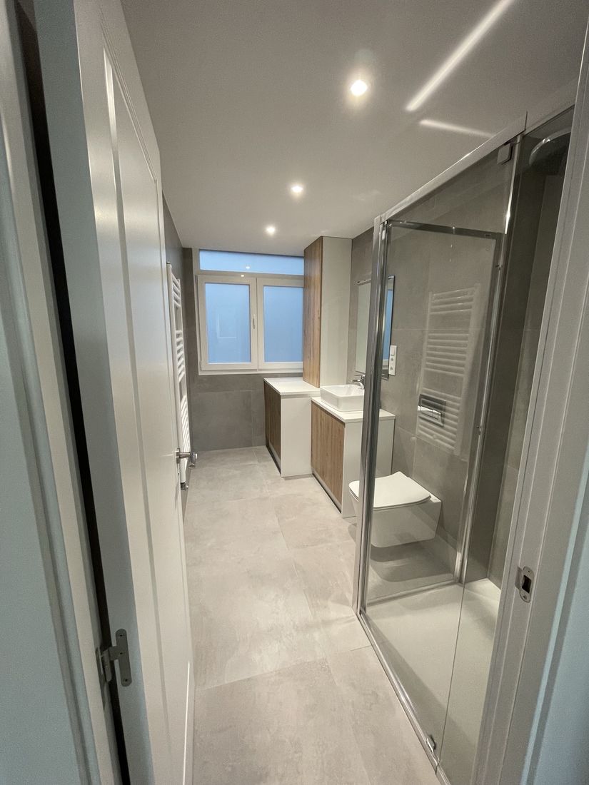Bathroom with grey large-format porcelain, wall-hung toilet and glass shower enclosure